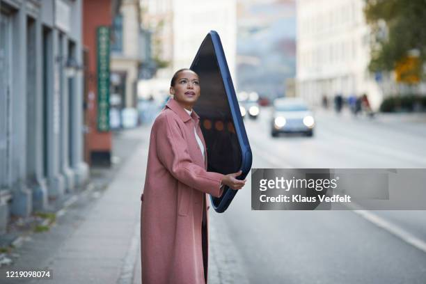 woman talking on large mobile phone on sidewalk in city - high angle view stockfoto's en -beelden