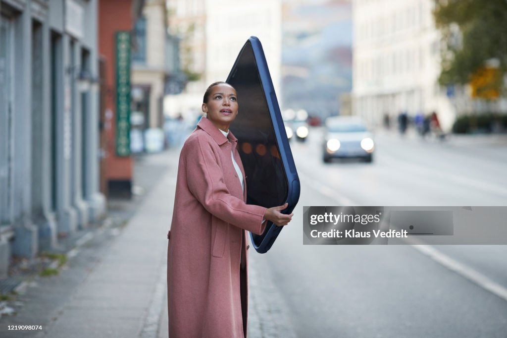 Woman talking on large mobile phone on sidewalk in city