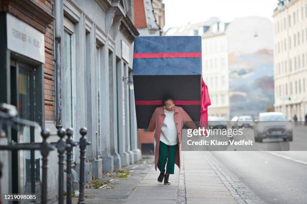woman carrying large gift box on sidewalk in city - big city life stock pictures, royalty-free photos & images