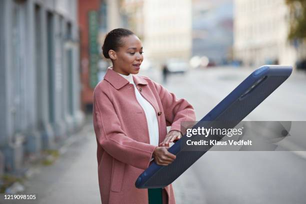 woman using large mobile phone while standing on sidewalk - phone comparison stock pictures, royalty-free photos & images
