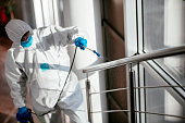Man in protective suit disinfecting steps in building stock photo