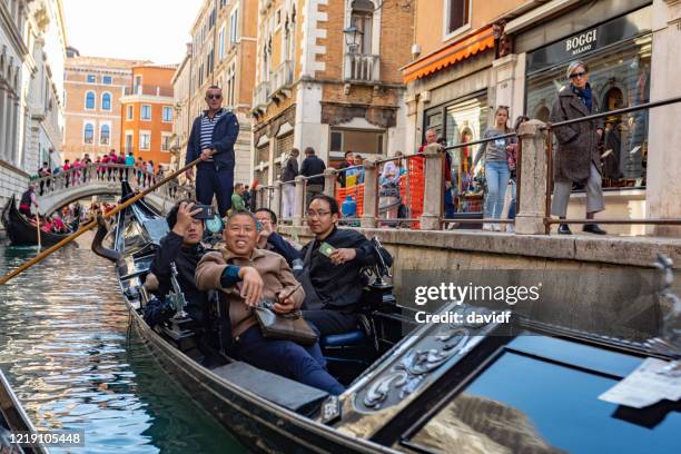 aziatische toeristen in een traditionele gondel op de kanalen van venetië, italië - gondola traditional boat stockfoto's en -beelden