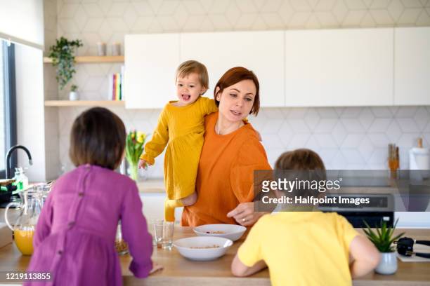 mother with three small children indoors in kitchen in the morning at home. - woman hurry 個照片及圖片檔