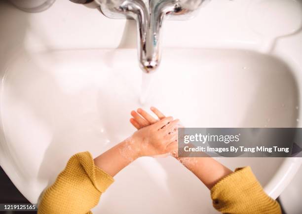 direct above view of a little girl washing her hands in sink - antiseptikum stock-fotos und bilder
