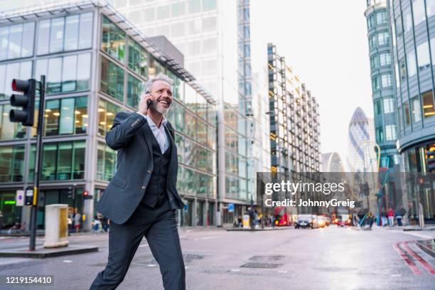lächelnder londoner geschäftsmann mit telefon beim überqueren der straße - offener kragen stock-fotos und bilder
