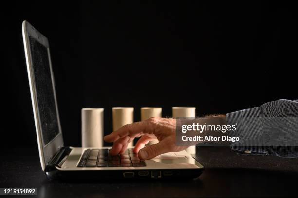 man´s hand  writing in a laptop. in the background there are just empty toilet rolls. - buying toilet paper photos et images de collection