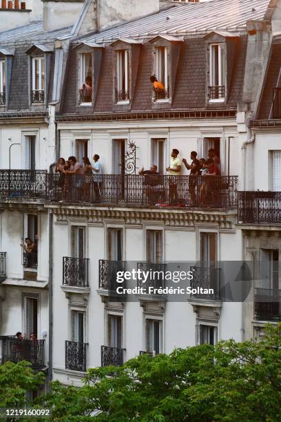 People applaud on their balcony at the neighborhood of "Gobelins" during the confinement of the French due to an outbreak of the coronavirus on April...