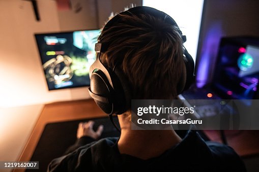 Vista trasera de Gamer con auriculares al jugar videojuegos en línea en Dark Room - foto de archivo Vista trasera de Gamer con auriculares al jugar videojuegos en línea en Dark Room - foto de archivo