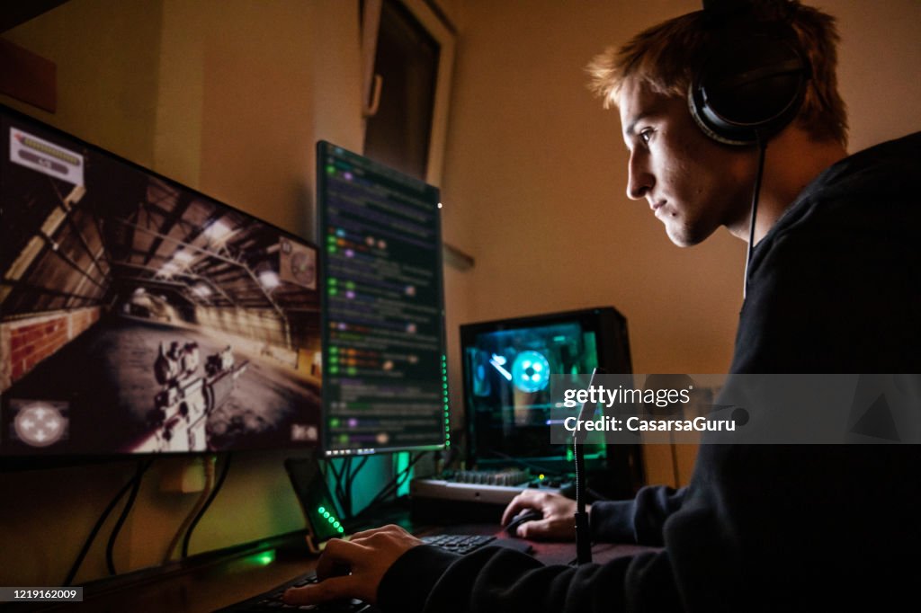 Teenage Boy Playing Multiplayer Games on Desktop Pc in his Dark Room - stock photo