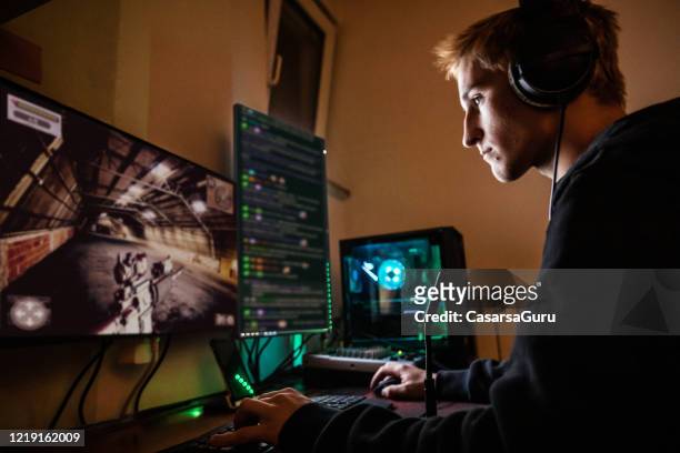 teenage boy playing multiplayer games on desktop pc in his dark room - stock photo - desktop pc stock pictures, royalty-free photos & images