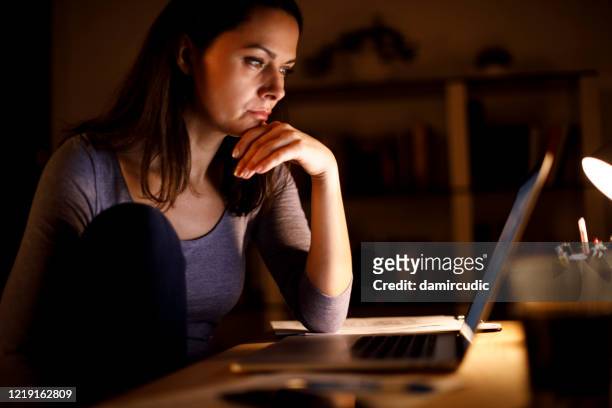 woman working on laptop late at home - unemployment benefits stock pictures, royalty-free photos & images