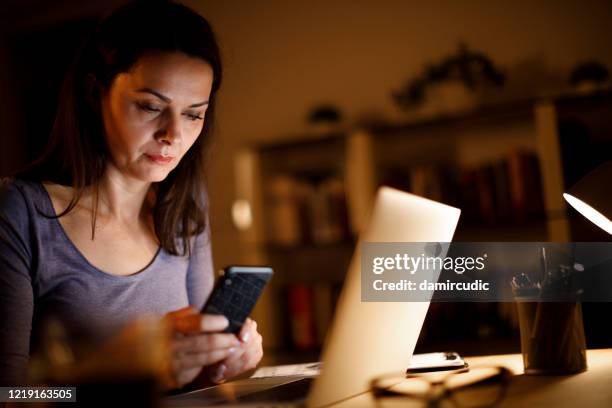 ongerust gemaakte rijpe vrouw die laat thuis werkt - isolated women serieus sad stockfoto's en -beelden