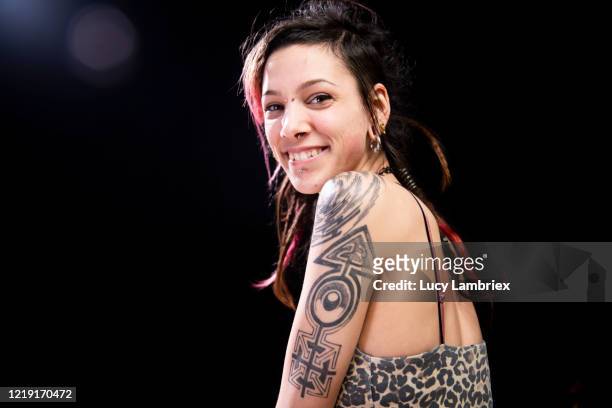 portrait of a smiling young woman with lens flare - tattoo shoulder stock-fotos und bilder