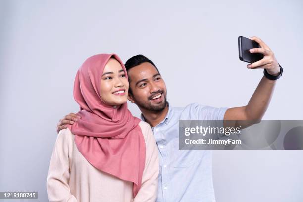 junge asiatische malaiische paar macht ein selfie zusammen auf dem handy - malay culture stock-fotos und bilder