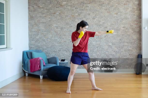 millennial woman practicing martial arts at home - muay thai stock pictures, royalty-free photos & images