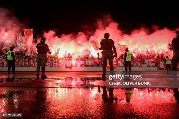Stewards and security personnel stand as Red Star supporters light flares during the Serbian Cup semi-final football match between FK Partizan...