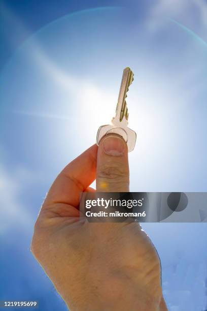 cropped hand holding a key against blue sky - ornate key stock pictures, royalty-free photos & images