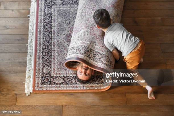 a father with a little son having fun together - carpet roll fotografías e imágenes de stock