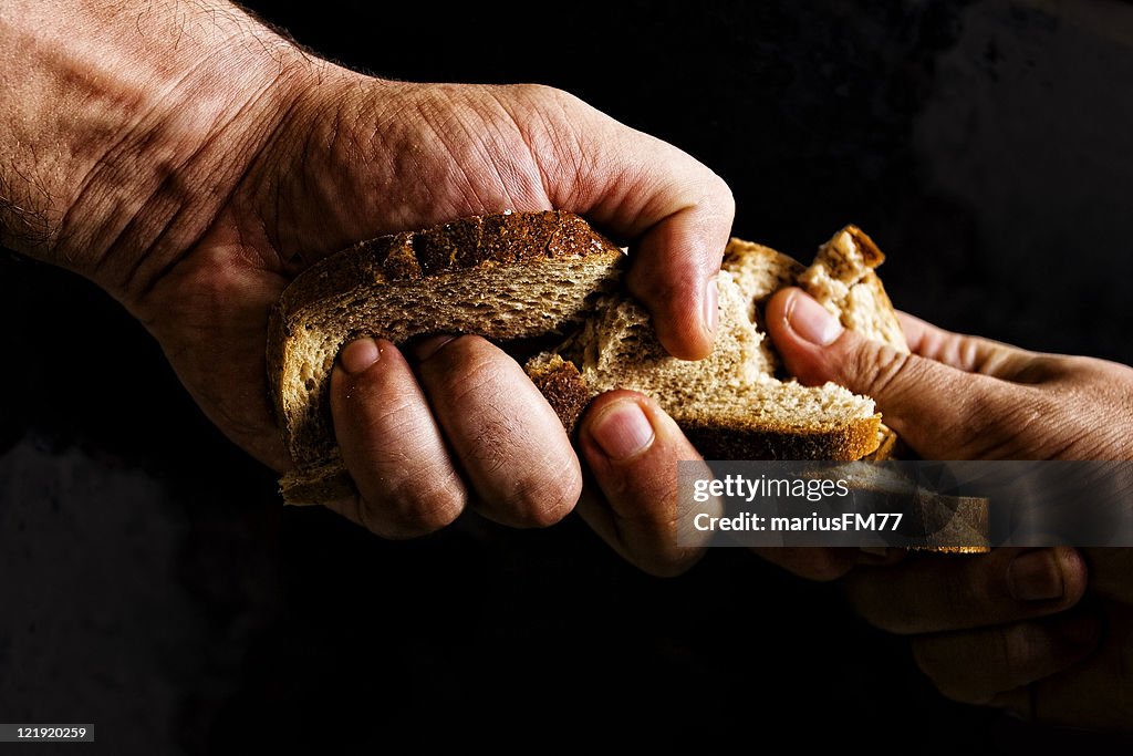 Two people fighting over piece of bread