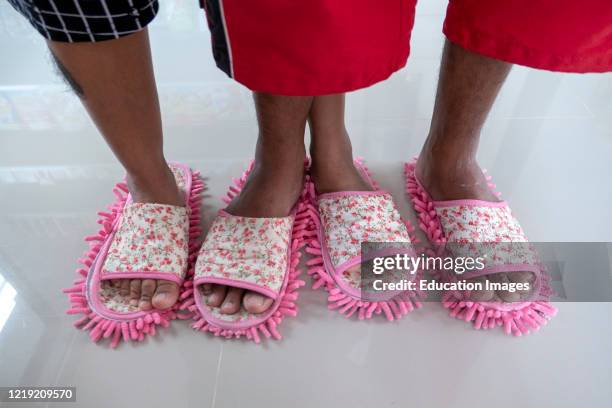 Store owners use floor cleaning slippers at beach shop Ko Tao Thailand.