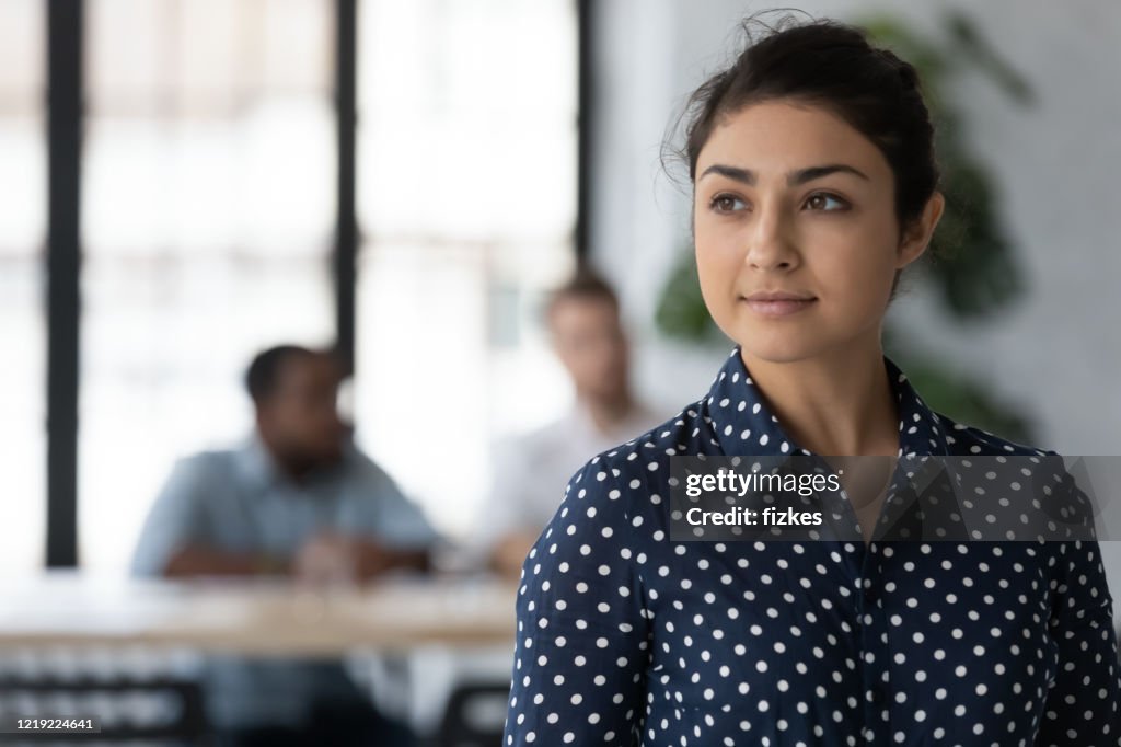 Female indian employee look in distance thinking of career opportunities