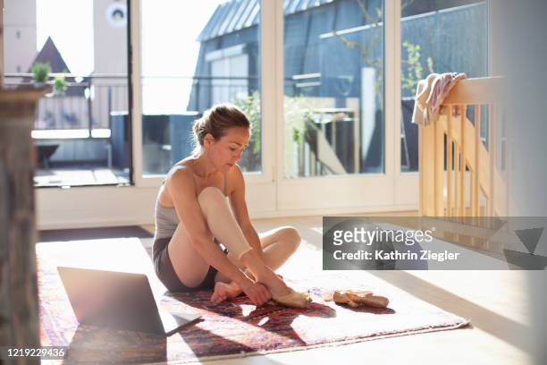 woman preparing for online ballet class at home, putting on pointe shoes - ballerina feet stockfoto's en -beelden