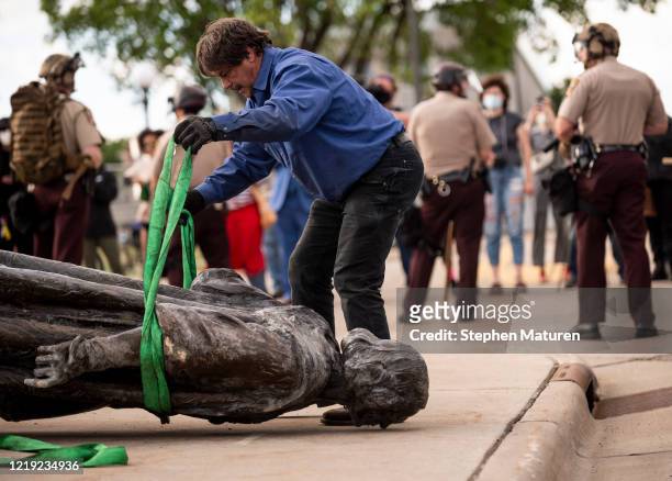 Statue of Christopher Columbus, which was toppled to the ground by protesters, is loaded onto a truck on the grounds of the State Capitol on June 10,...