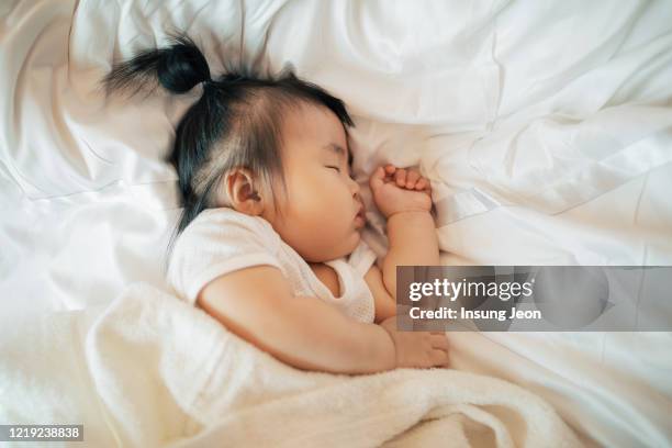 baby girl sleeping on bed - baby girls fotografías e imágenes de stock