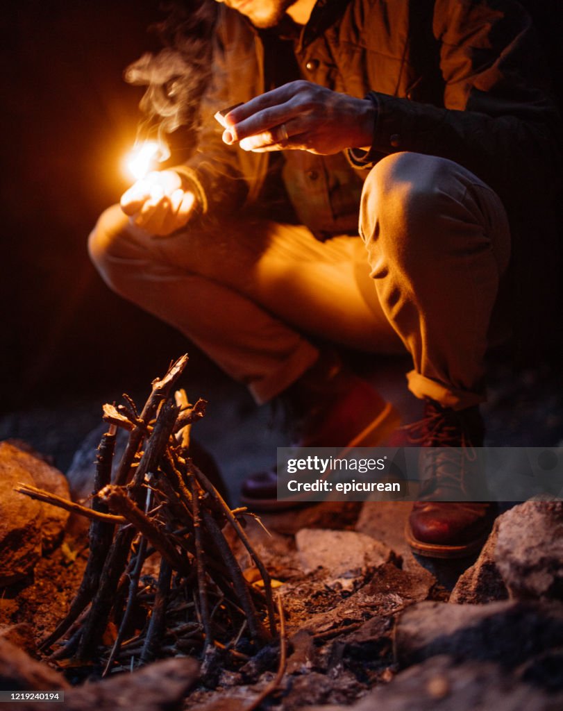 Man lighting a fire at dusk on a camping trip in New York