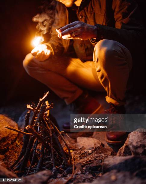 man lighting a fire at dusk on a camping trip in new york - wilderness camping stock pictures, royalty-free photos & images