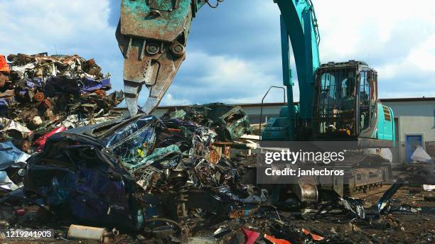 giornata intensa in discarica. artiglio meccanico che smonta vecchie auto - demolito foto e immagini stock