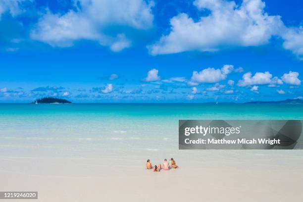 friends sit in the warm clear waters. - whitehaven beach stock pictures, royalty-free photos & images