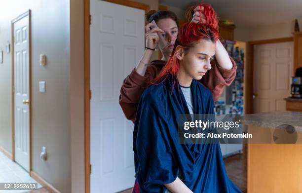 older sister cutting her younger sister's hair at home. - alex potemkin coronavirus stock pictures, royalty-free photos & images