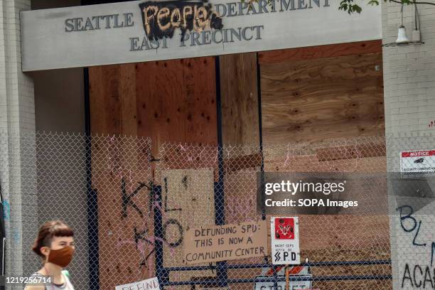 Woman walks in front of the seemingly abandoned East Precinct station of the Seattle Police Department. Protesters declared a Cop Free Zone near...