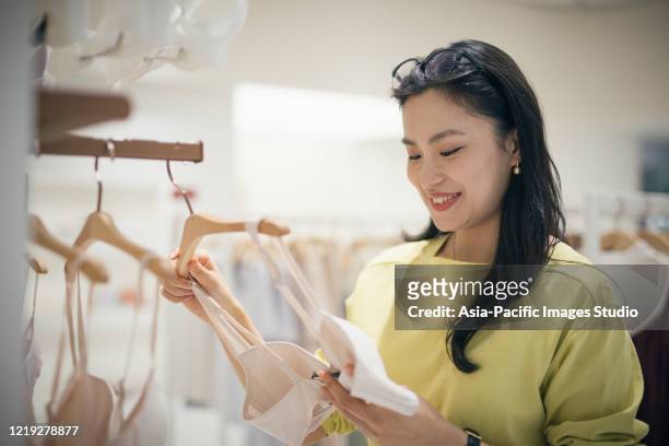young asian woman choosing new bra in the clothing store. - bra stock pictures, royalty-free photos & images