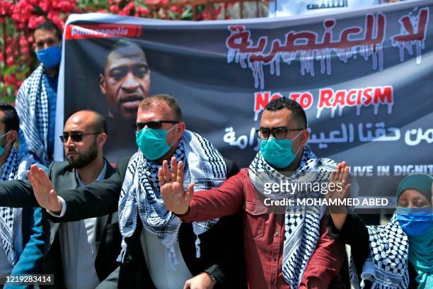 Palestinians gesture as others lift a banner protesting the killing of Iyad Hallak, an autistic Palestinian man shot dead by Israeli police, and that...