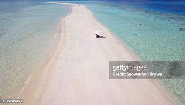 sandbar island with beach umbrella and chair, people walking in distance, aerial establishing shot of the maldives - 無人島 ストックフォトと画像