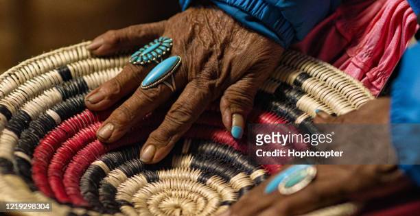 eine ältere indianerin (navajo) trägt türkisfarbene ringe an ihren fingern berührt einen gewebten navajo-korb - aboriginal artwork stock-fotos und bilder