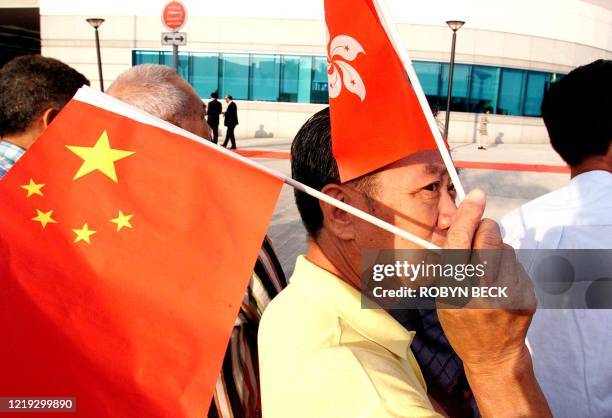 Man waves the Chinese and Hong Kong flags before the Chinese National Day holiday as he waits to view the flag raising ceremony to celebrate Chinese...