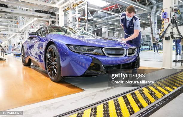 June 2020, Saxony, Leipzig: The last BMW i8 is at the end of the One employee wipes the last BMW i8 with a cloth at the end of the production line....