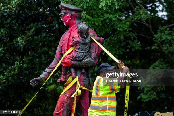 Workers remove a police memorial statue covered in red paint by protesters on June 11, 2020 in Richmond, Virginia. Protesters also tore down statues...