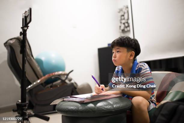 ein schüler lernt während der covid-19-pandemie zu hause mit einem mobiltelefon-e-klassen. fernunterricht online-ausbildung oder zu hause bleiben. - studiengebühren stock-fotos und bilder
