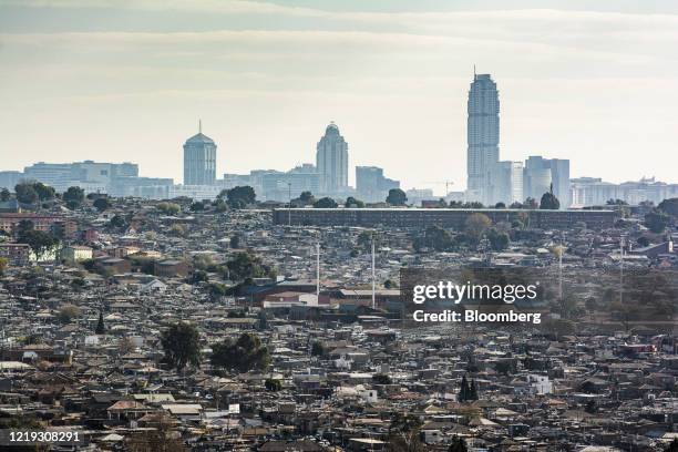 Skyscraper office buildings in the Sandton area stand on the skyline beyond residential housing in the Alexandra township in Johannesburg, South...