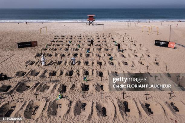 Aerial view of activists from the Brazilian NGO Rio de Paz digging mock graves, on Copacabana beach symbolizing deaths due to the COVID-19...