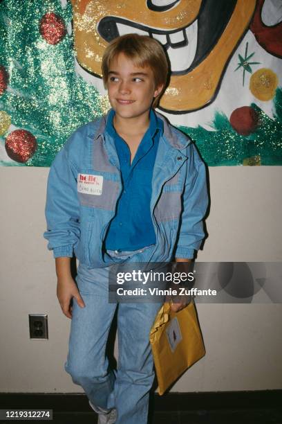 American actor Chad Allen, wearing a blue jacket, with the sleeves rolled up, over a blue shirt and blue denim jeans, and holding a brown envelope,...