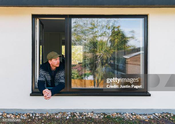 man looking out of bedroom window - marco de ventana fotografías e imágenes de stock