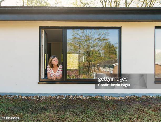 senior woman looking out of her bedroom window - green roof stock pictures, royalty-free photos & images