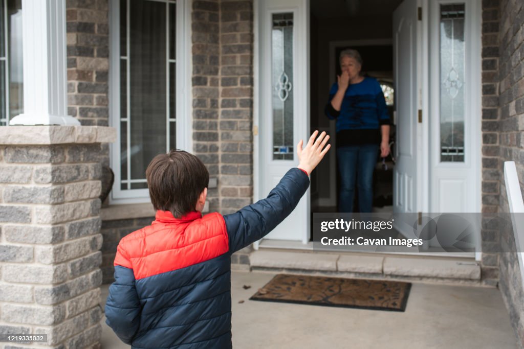 Social distance visit between young boy and his grandmother at home.