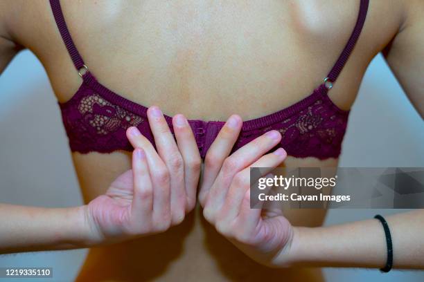 woman putting on a fuchsia bra. - beha stockfoto's en -beelden