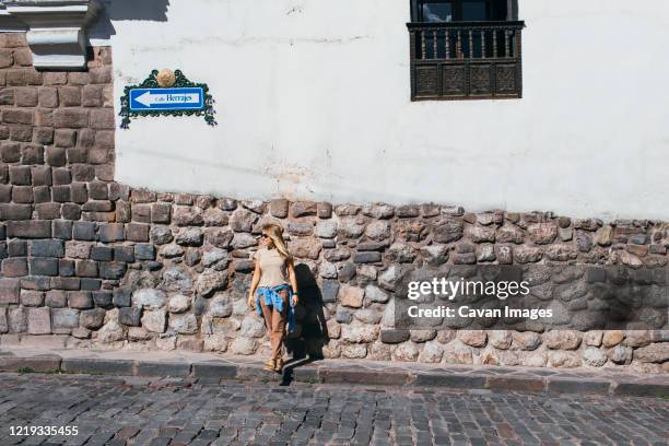 a young woman is standing near a white wall in cusco, peru - cuzco fotografías e imágenes de stock